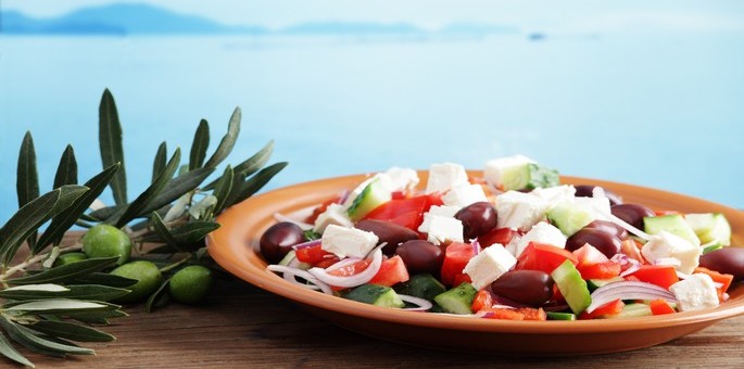 Oval sa grčkim jelima, pozadina mediteransko more.